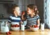 Media Release: Free and Reduced-Price School Meals Two chidren sitting at a table. The little girl is giving the little boy a strawberry. They have bowls of strawberries and glasses of milk on the table in front of them.