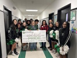 Cheerleaders and grant winner with a giant check